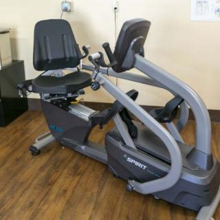 A recumbent exercise bike positioned on a wooden floor in a fitness setting.