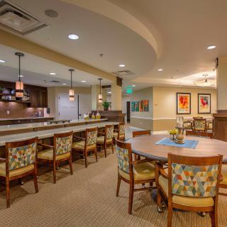 A cozy dining area with a long counter and chairs, featuring warm lighting and artistic decor.