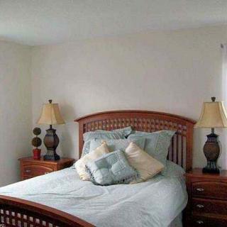 A cozy bedroom with a neatly made bed and two bedside lamps.