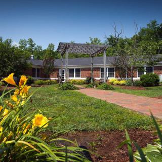 A scenic view of a building surrounded by a lush garden with vibrant flowers and trees.