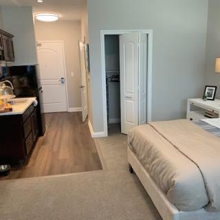 A modern and minimalist apartment featuring a cozy bedroom with an adjacent kitchenette.