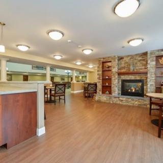 A spacious lounge area with wooden flooring, comfortable seating, and a warm fireplace.