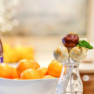 A table featuring a bowl of oranges and dessert skewers with a mint garnish.