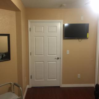 A simple room interior with a door, wall-mounted television, and a mirror.