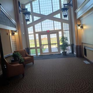 A spacious lobby with large windows allowing natural light, featuring comfortable seating and decorative plants.