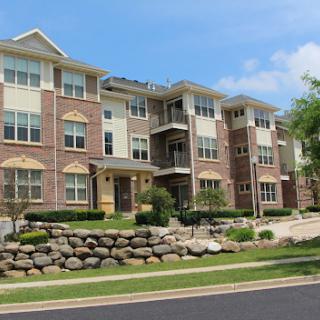 A modern apartment complex featuring multiple levels with brick facades and landscaped surroundings.