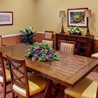 A well-decorated dining room with a wooden table, chairs, floral centerpiece, and wall art.