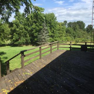 A wooden deck overlooking a lush green landscape under a clear sky.
