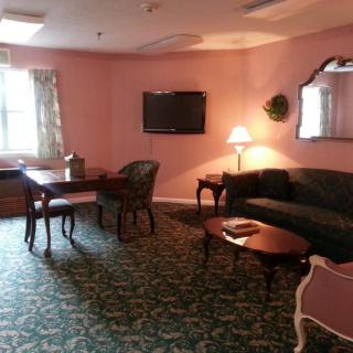 A cozy living room with pink walls, featuring a sofa, table, lamp, and television.