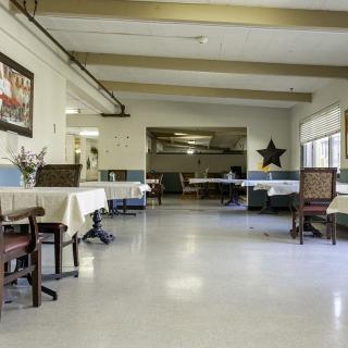 An empty dining area with neatly arranged tables and chairs, decorated with wall art and a star ornament.