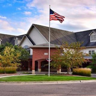 A building with an American flag flying in front, surrounded by trees and a clear sky.