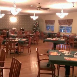 An elegantly decorated dining room with neatly arranged tables and a Christmas tree in the corner.