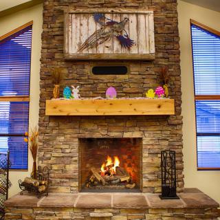 A cozy stone fireplace with a wooden mantel, decorated for the season.
