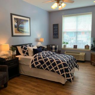 A cozy bedroom with modern decor, featuring a bed with patterned bedding, a large window, and stylish furniture.