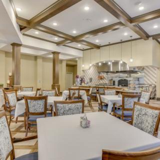 A cozy dining area with neatly arranged tables and chairs, featuring warm lighting and elegant interior design.