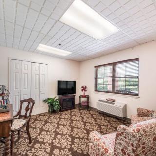A cozy living room with a patterned carpet, television, and classic wooden furniture.