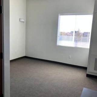 An empty room with a carpeted floor and a window allowing natural light in.