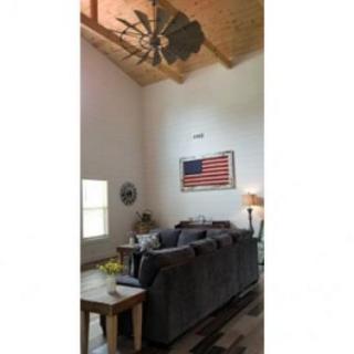 A cozy living room with a large sofa and an American flag on the wall.