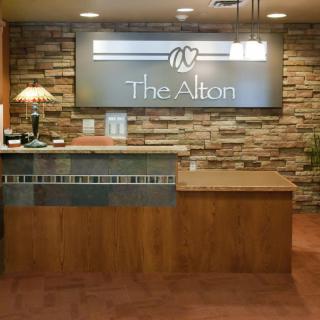 A modern reception area with a wooden desk and stone wall backdrop.