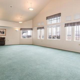 Spacious living room with large windows and green carpet.