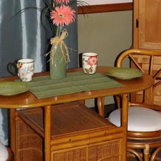 A cozy dining setup featuring a wooden table, decorative flower vase, and two patterned mugs.