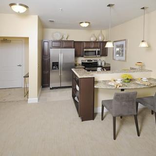 A modern kitchen with stainless steel appliances and a small dining area.