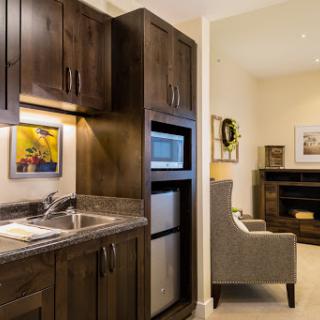 A cozy kitchenette featuring dark wood cabinets, modern appliances, and a comfortable living area.