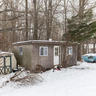 A small cabin in a snowy forest setting, surrounded by trees.