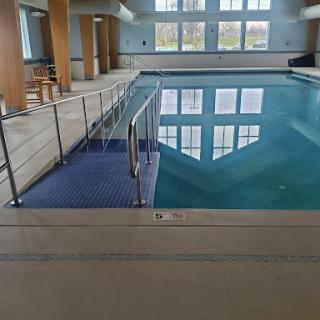 A spacious indoor swimming pool with accessible features and large windows allowing natural light.