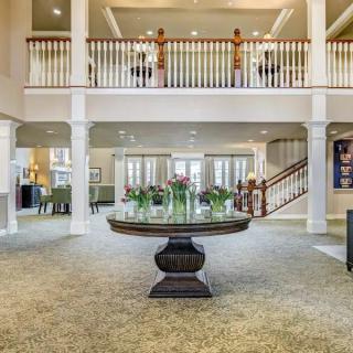 Spacious, elegantly decorated lobby with a central table and staircase.