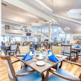 A spacious and elegantly designed restaurant dining area with neatly arranged tables and blue napkins.