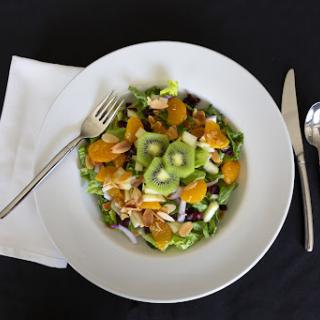 A vibrant and fresh salad featuring a mix of greens, fruits, and nuts.