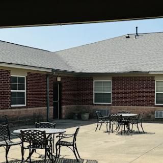 A view of a courtyard featuring outdoor tables and a brick building under clear skies.