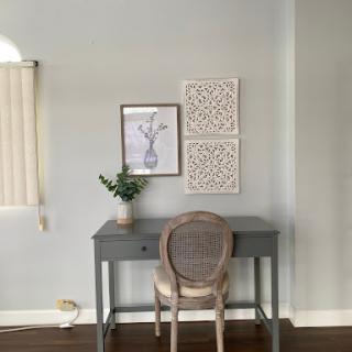 A serene and minimalist workspace featuring a stylish desk, an elegant chair, and tasteful wall dcor.