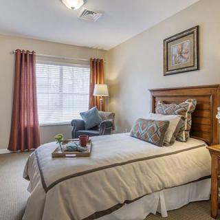 A cozy and well-decorated bedroom with a single bed, wooden furniture, and natural light coming through the window.