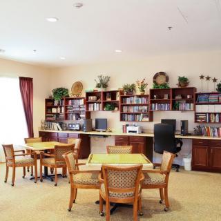 A cozy library interior with tables, chairs, and bookshelves filled with books and decorative items.