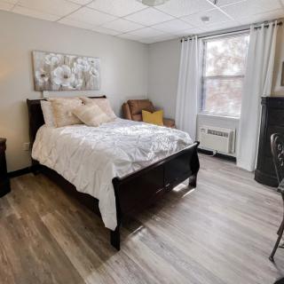 A modern, minimalist bedroom with wood flooring and ample natural light.