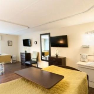 A well-lit hospital room featuring a bed, television, and comfortable furnishings.