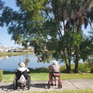Two elderly individuals enjoying a peaceful moment by the lake in a beautiful park.