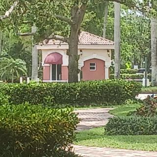 A quaint building surrounded by lush greenery and a paved pathway.