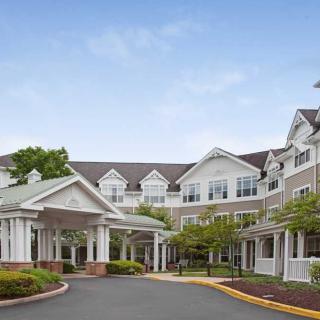 A white, multi-story residential building with landscaped surroundings and a welcoming entrance.
