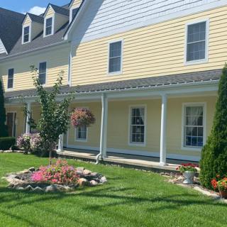 A charming yellow house with a well-maintained lawn and colorful garden.