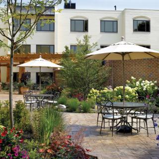 A beautifully landscaped garden patio with tables and chairs under large umbrellas.