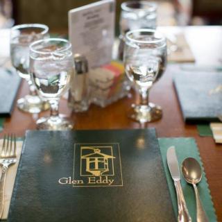 A restaurant table set with menus, glassware, and silverware.