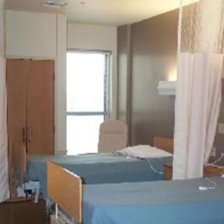 A hospital room with beds and privacy curtains.