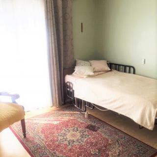 A simple bedroom with a single bed and natural light streaming through the window.