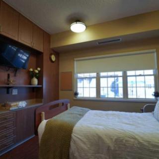 A neatly arranged hospital room with a bed and television.