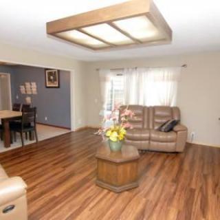 A cozy living room with hardwood floors, featuring a leather sofa set and a wooden coffee table.