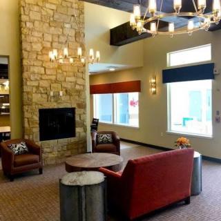 A cozy lounge with a stone fireplace, comfortable seating, and a modern chandelier.