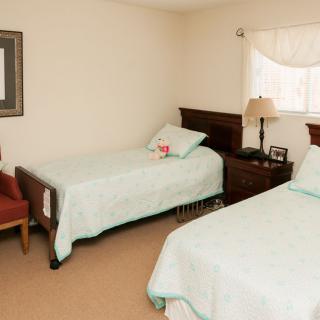 A tidy bedroom with two twin beds, a nightstand, and a lamp.